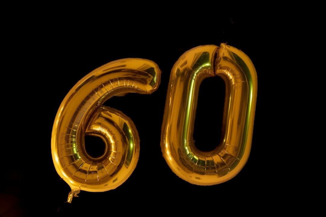 Gyldne ballonnumre, der viser tallet 60 på sort baggrund